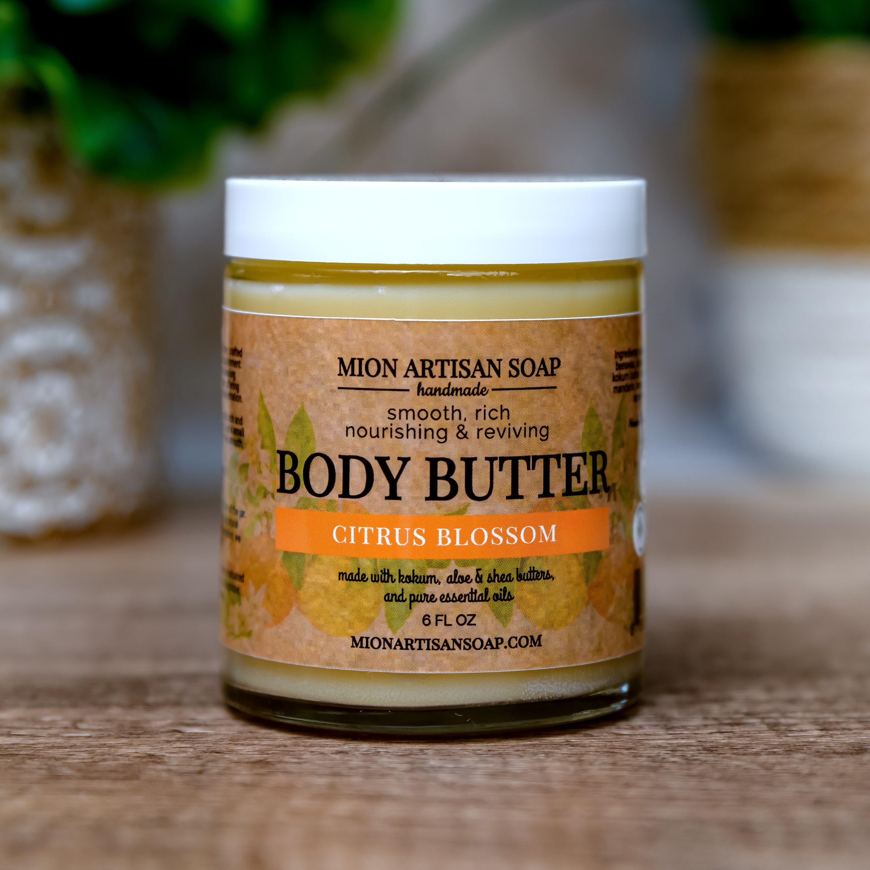 Jar of Mion Artisan Soap body butter with a blurred green plant in the background