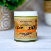 Jar of Mion Artisan Soap body butter with a plant in the background
