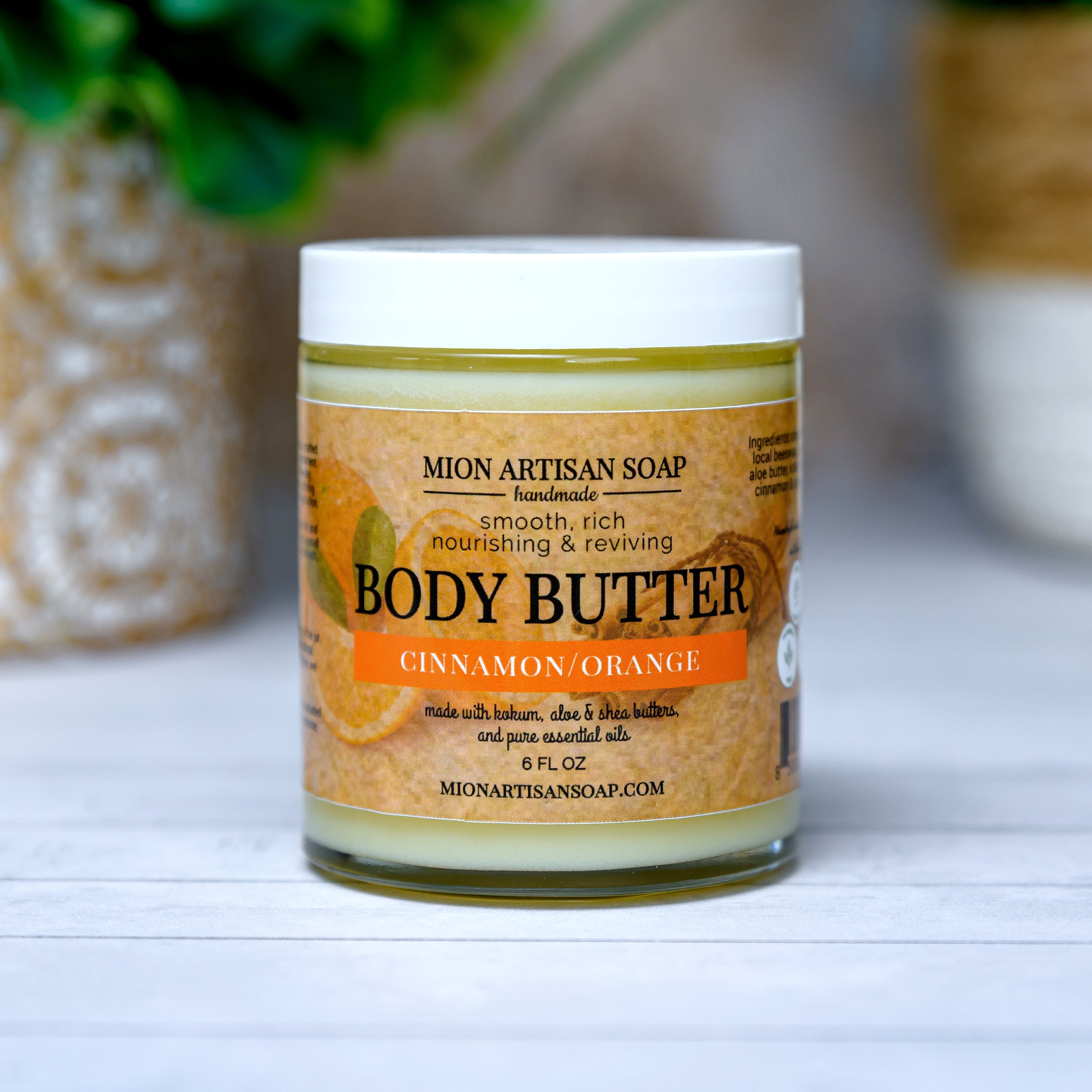Jar of Mion Artisan Soap body butter with a plant in the background