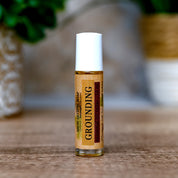 Roll-on bottle labeled 'Grounding' on a wooden surface with a blurred natural background