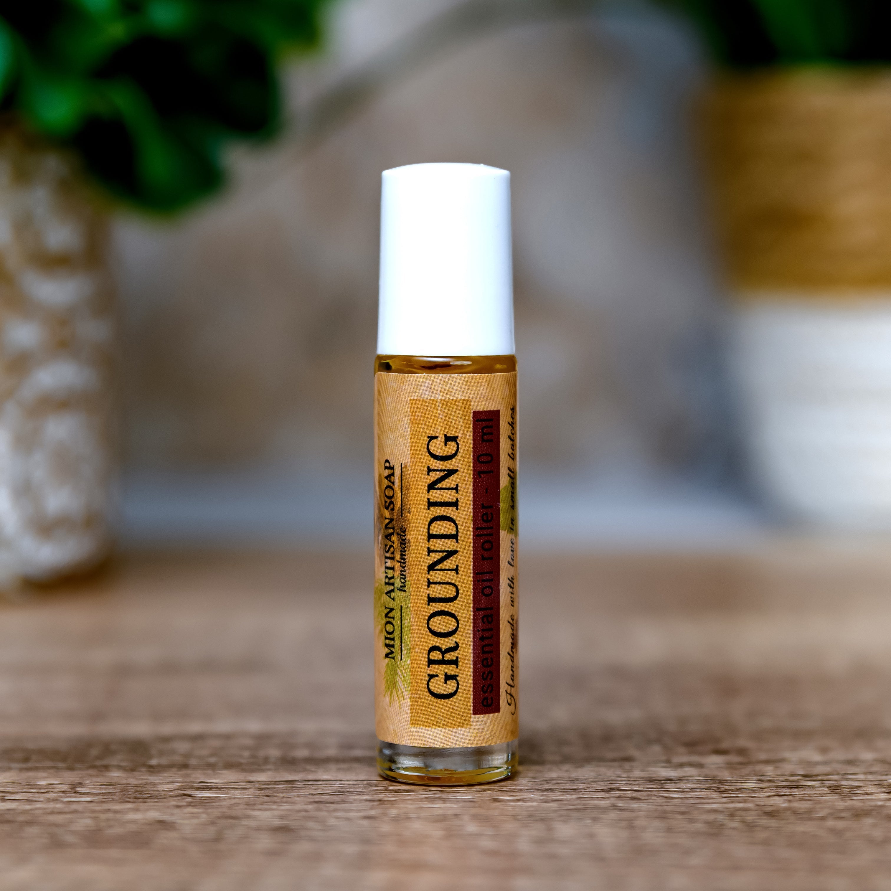 Roll-on bottle labeled 'Grounding' on a wooden surface with a blurred natural background