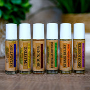 Set of six essential oil roller bottles with labels on a wooden surface.