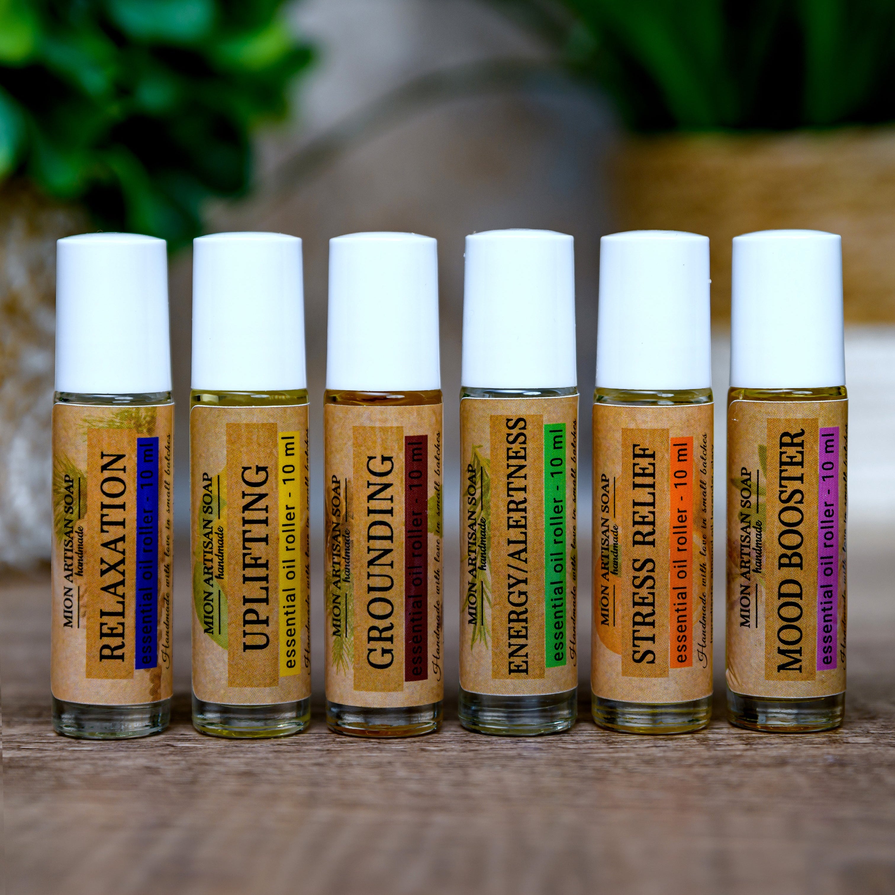 Set of six essential oil roller bottles with labels on a wooden surface.
