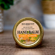 Hand balm container with 'Mion Artisan Soap' label on a wooden surface.