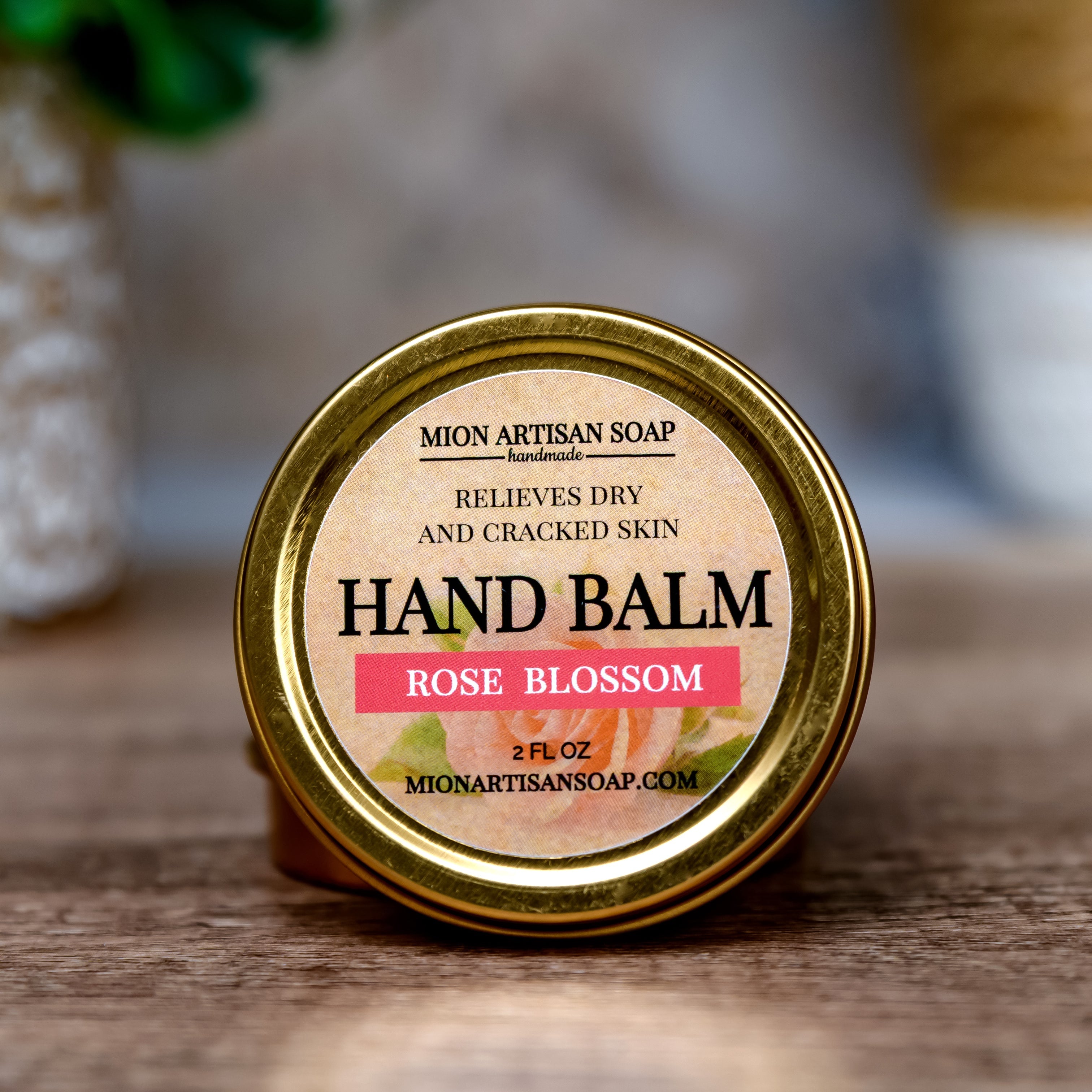 Hand balm container with 'Rose Blossom' label on a wooden surface