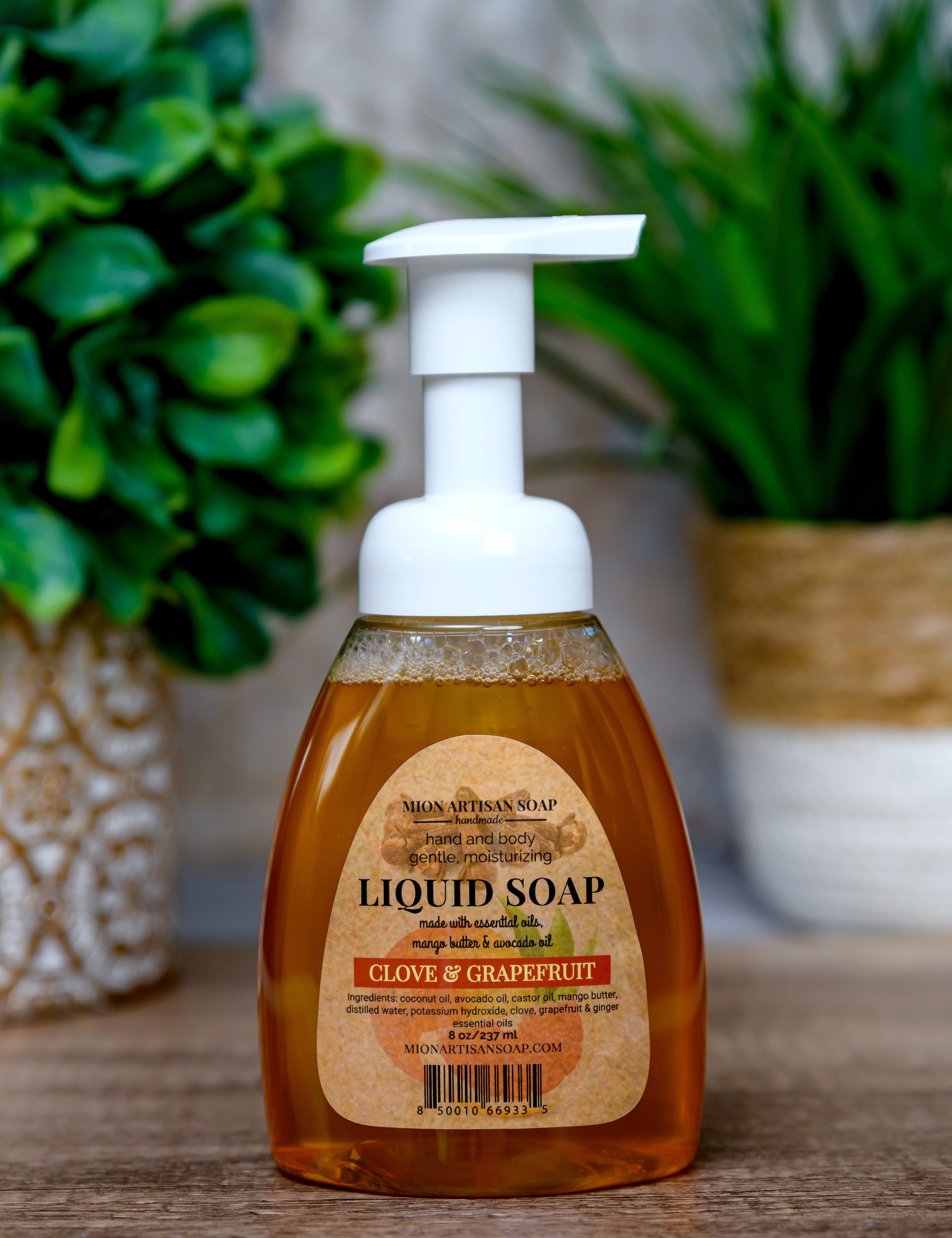 Bottle of liquid soap with a label on a wooden surface with plants in the background