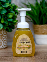 Liquid soap bottle with pump on a wooden surface with plants in the background