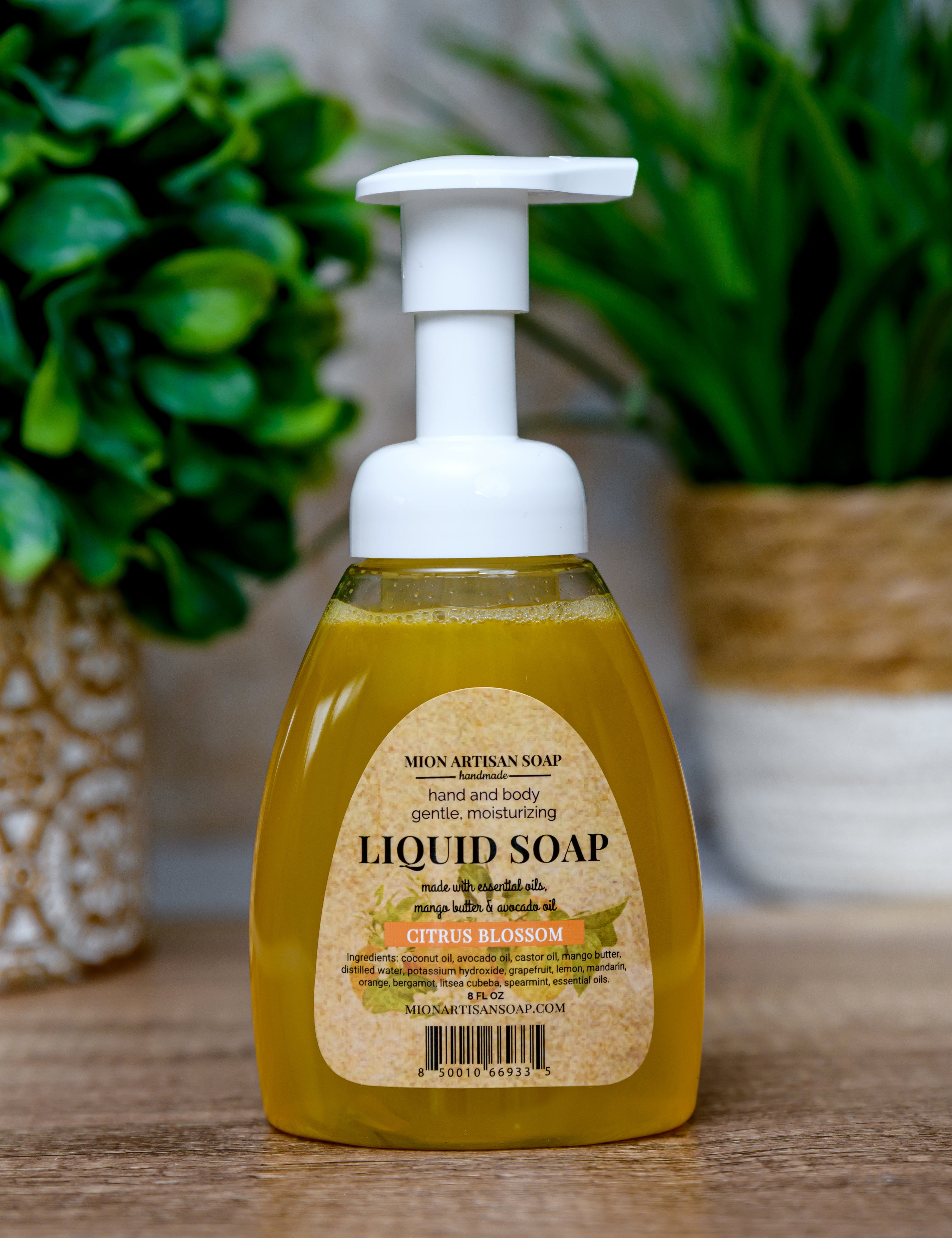 Liquid soap bottle with pump on a wooden surface with plants in the background