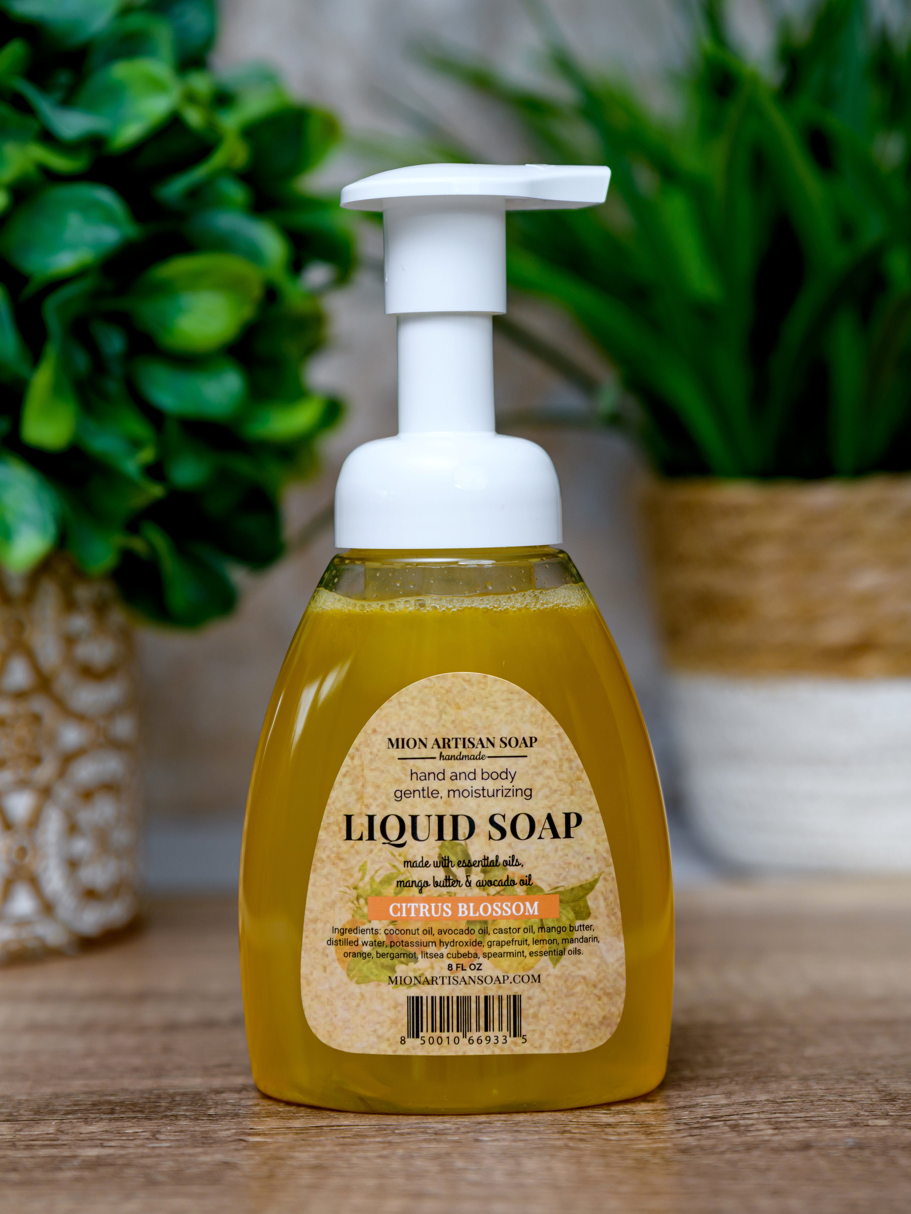 Liquid soap bottle with pump on a wooden surface with plants in the background