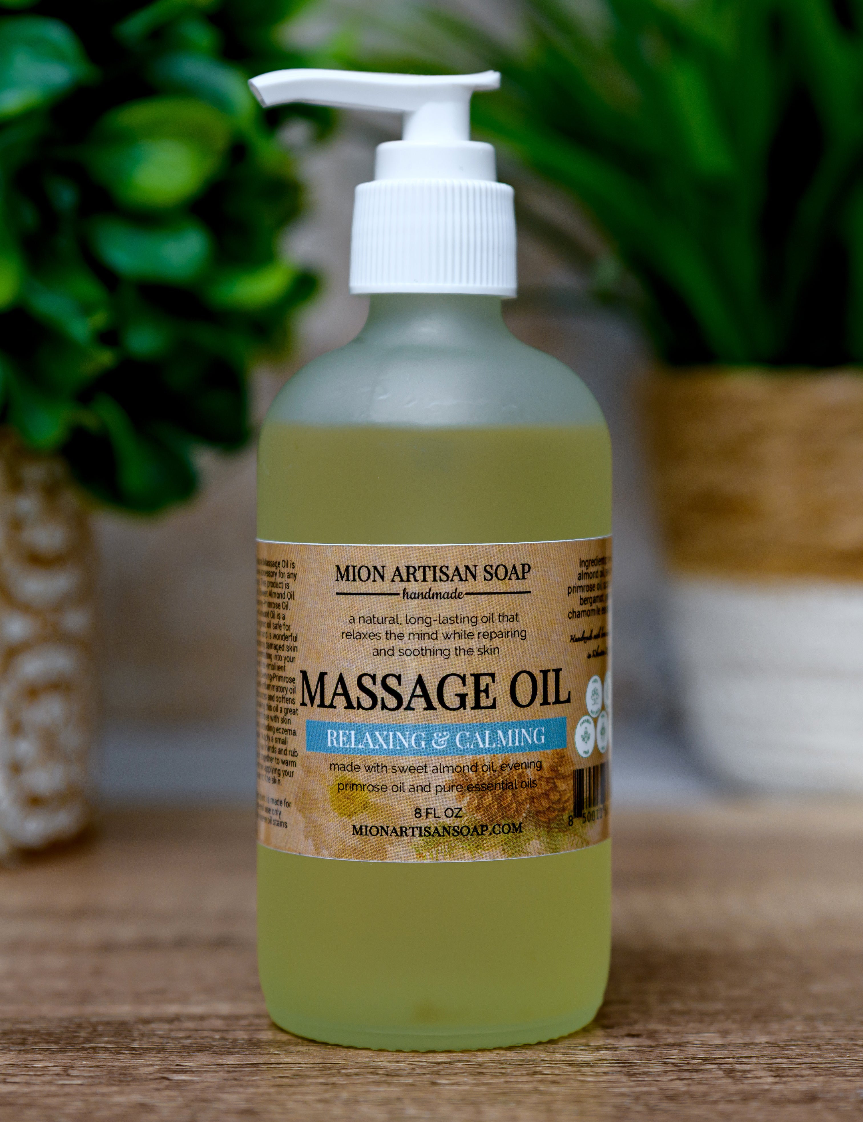 Bottle of Mion Artisan Soap massage oil on a wooden surface with plants in the background